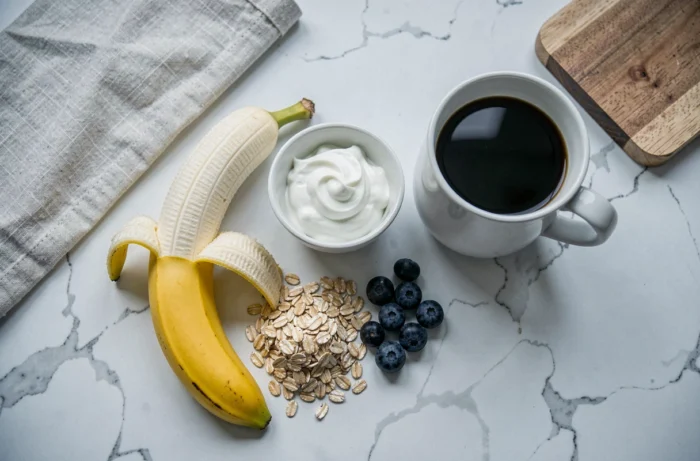 Vue du dessus d'un petit déjeuner équilibré avec une banane, du yaourt grec, des flocons d'avoine et du café
